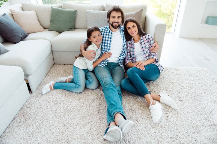 Family smiling on clean carpet and protected from the Coronavirus.