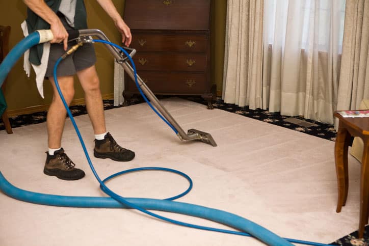 Carpet cleaner with hose and wand cleaning older home.