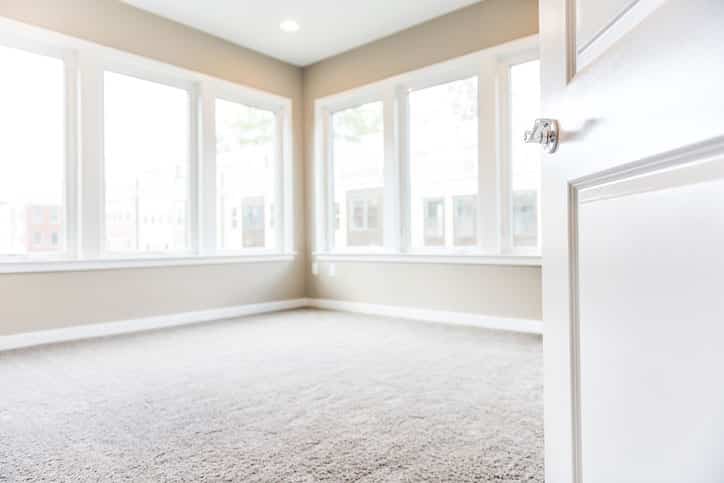 Picture of white carpet room with many windows.