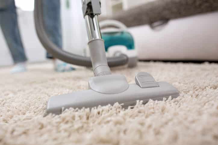 Woman using vacuum cleaner at home in the living room